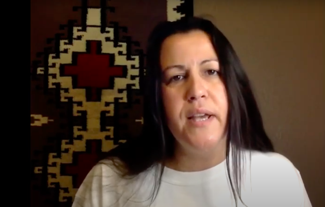 Natalie Diaz reading in front of a wall hanging