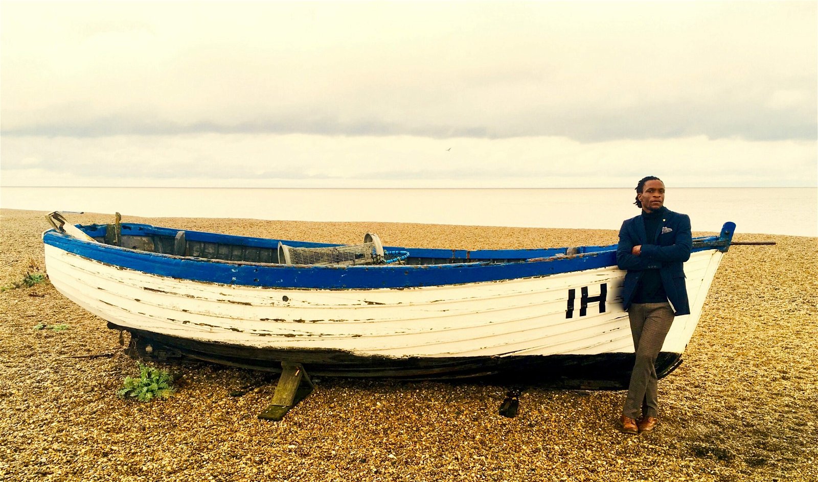 Poet Ishion Hutchinson on a beach by a boat