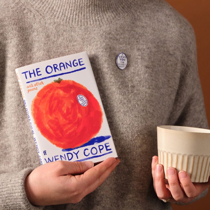 Model holding The Orange poem book and wearing pin badge